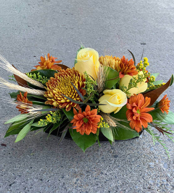 An image of an autumn table arrangement, with yellow roses, sunflowers and daisies