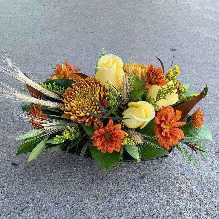 An image of an autumn table arrangement, with yellow roses, sunflowers and daisies