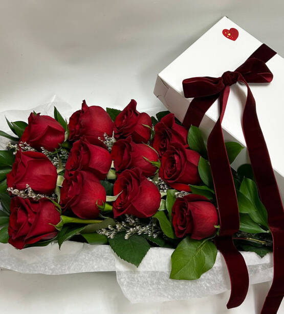 a dozen boxed red roses with a red ribbon on the box