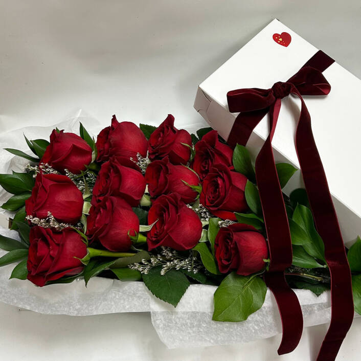 a dozen boxed red roses with a red ribbon on the box