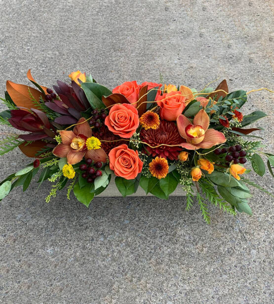 a orange pink and yellow fall arrangement in a wooden rectangular box