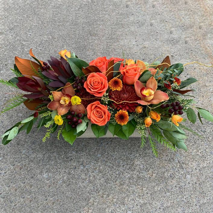 a orange pink and yellow fall arrangement in a wooden rectangular box