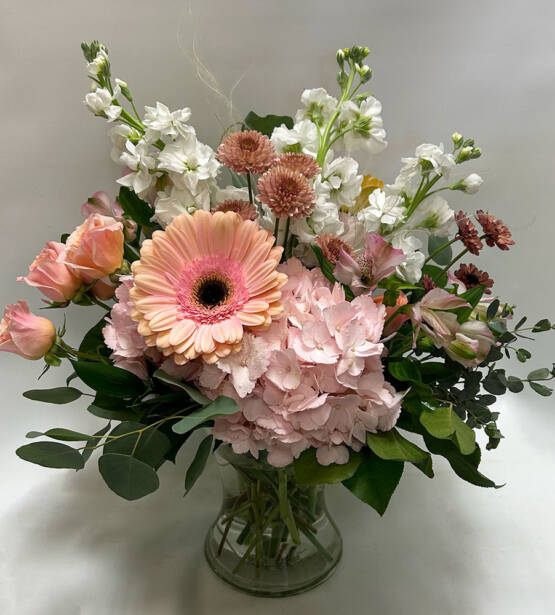 a pink and white floral arrangement in a glass vase